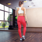 femme vue de dos faisant de la corde à sauter en legging rose