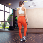 femme vue de dos faisant de la corde à sauter en legging orange