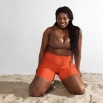 une femme portant un short orange à genoux dans du sable