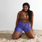 une femme portant un short violet à genoux dans du sable