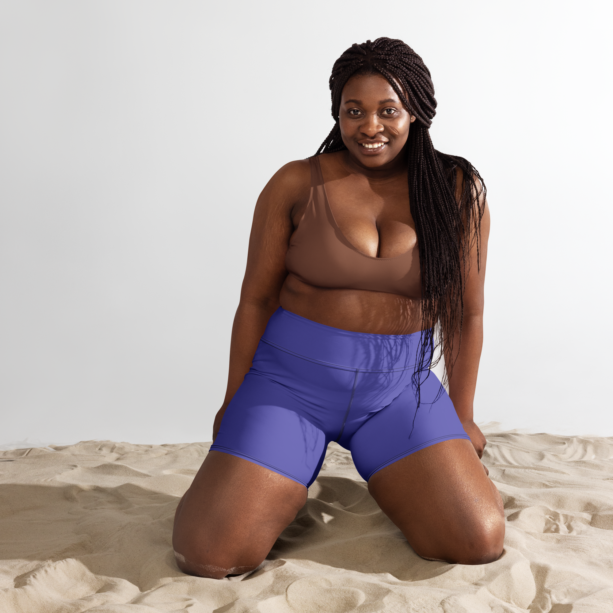 une femme portant un short violet à genoux dans du sable