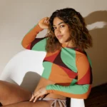 Crop top de sport Hot Focus à manches longues, motif géométrique au couleur vert d'eau, brun, rouge et orange, conçu pour allier confort et style lors des entraînements. Photo porté par le mannequin taille S assise dans un fauteuil.