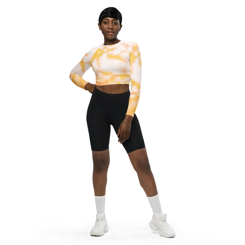 Crop top de sport Hot Focus à manches longues, motif tie and dye jaune et blanc, conçu pour allier confort et style lors des entraînements. Photo du produit porté par le mannequin de face, main sur la hanche.